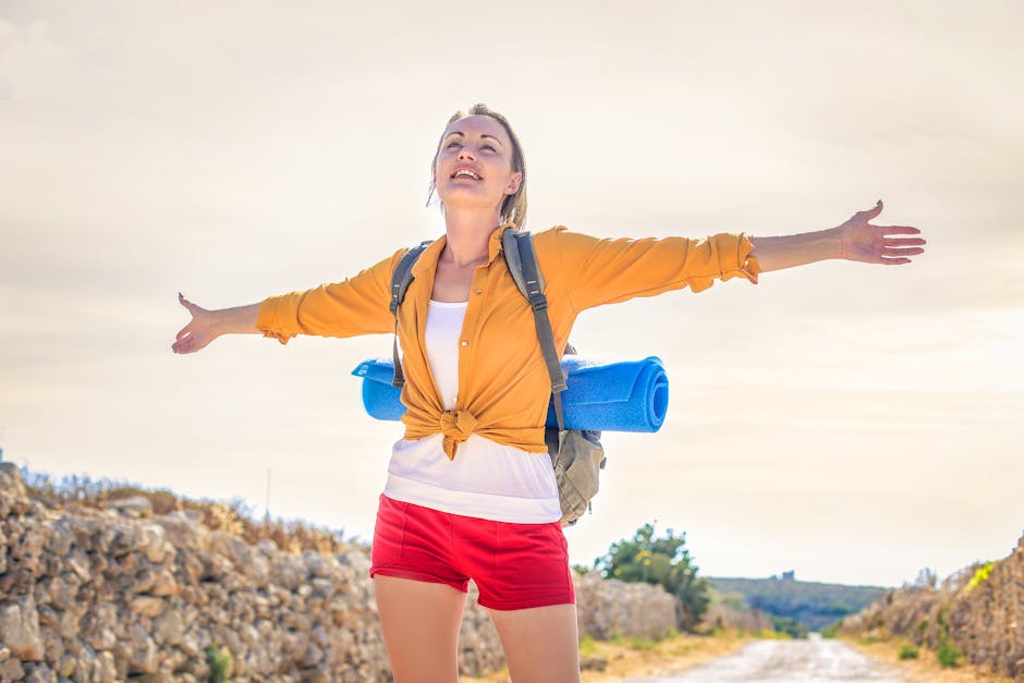 Happy woman basking in sunlight on a summer hike with yoga mat